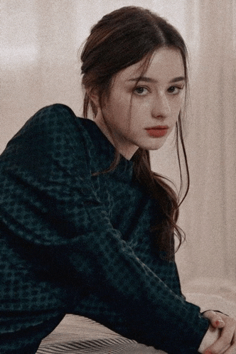 a girl in a leopard print sweater is sitting on a bed