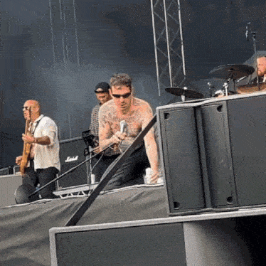 a man with tattoos on his chest is singing into a microphone