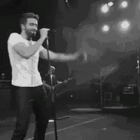 a man with a beard is singing into a microphone on a stage .