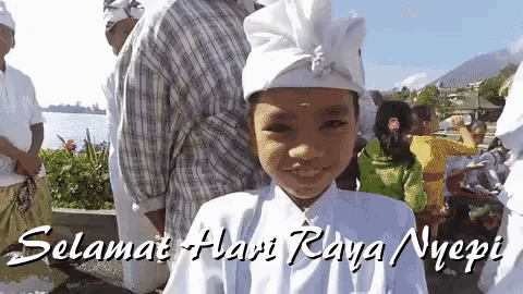 a young boy wearing a white hat with the words selamat hari raya nyepi written below him