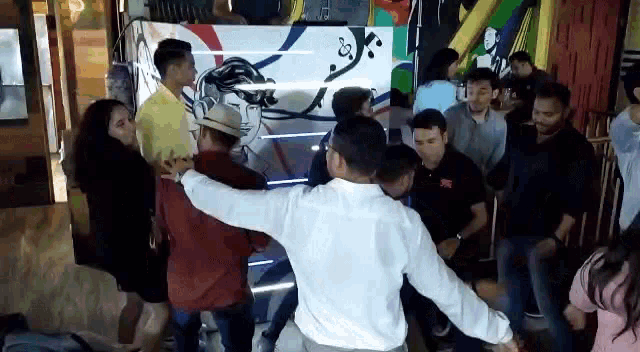a group of people are dancing in a room with a dj in the background .