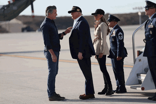 a man wearing a military hat talks to a man in a suit