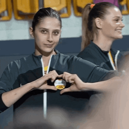 two women are making a heart shape with their hands in front of a nike logo
