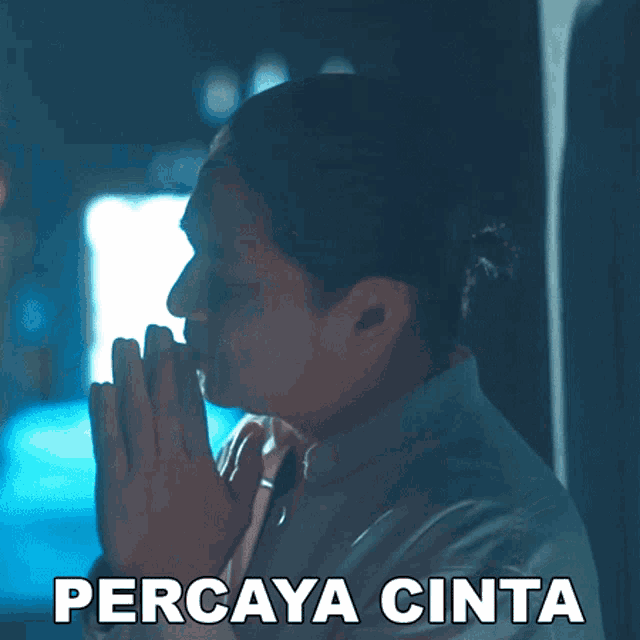 a man with his hands folded in front of his face and the word percaya cinta written below him