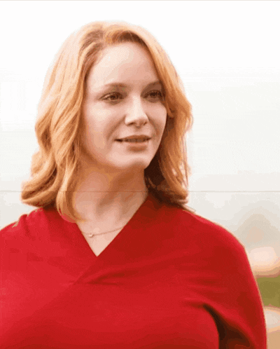 a woman with red hair is wearing a red shirt and necklace