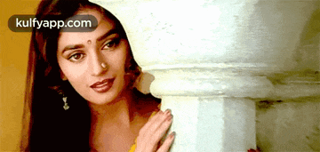 a woman peeking out from behind a pillar with a kulfyapp.com logo on the bottom right