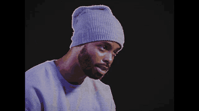 a pixelated image of a man wearing a purple beanie