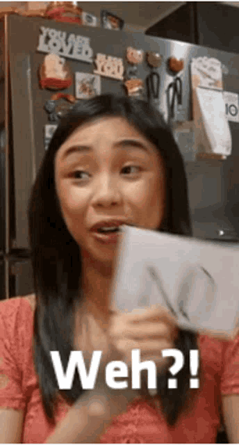 a woman in a pink shirt is holding a piece of paper that says weh on it .