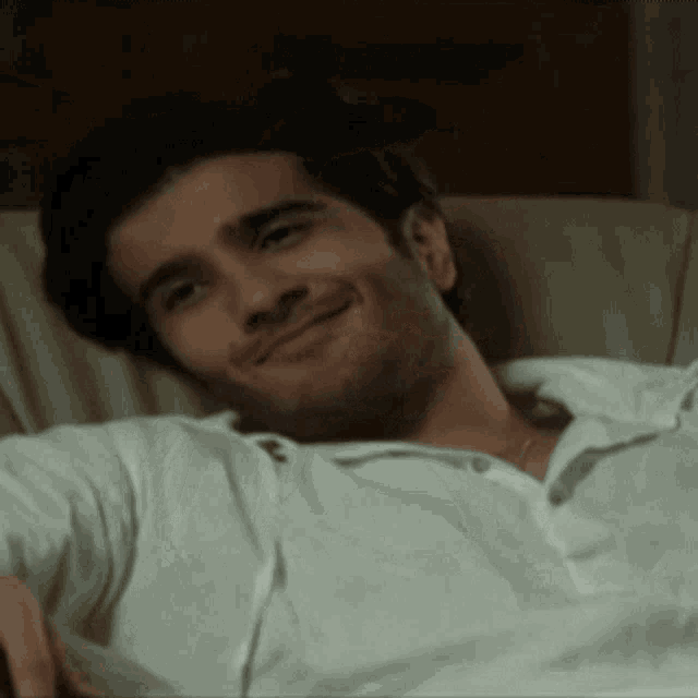 a man in a white shirt is smiling while laying down