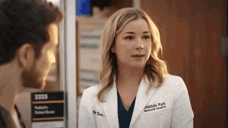 a woman in a white lab coat is talking to a man in a hospital .