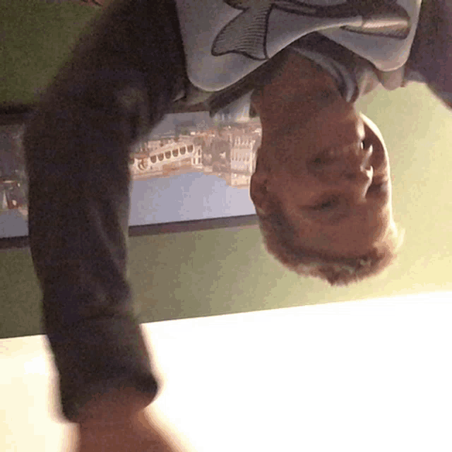 a boy wearing a shirt with a whale on it is hanging upside down