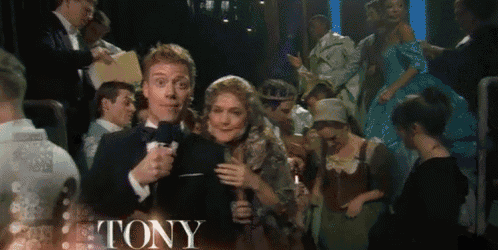 a man in a tuxedo is holding a microphone and the word tony is on the bottom of the image