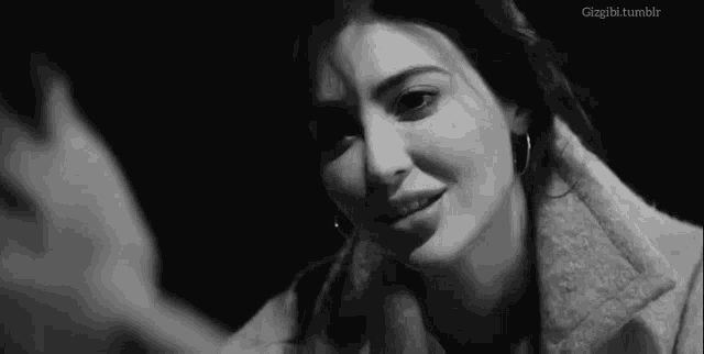 a black and white photo of a woman looking at a man in a dark room .