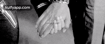 a black and white photo of a man and woman holding hands .