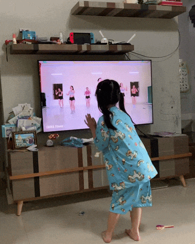 a little girl is dancing in front of a tv screen that says zumba fitness