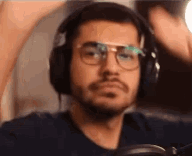 a man wearing headphones and glasses is sitting in front of a microphone .