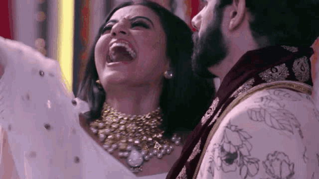 a man and a woman are laughing together while standing next to each other .