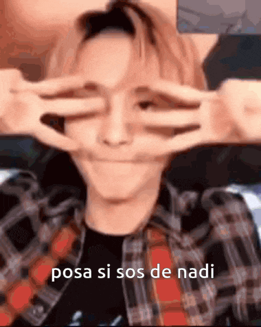 a man in a plaid shirt is making a peace sign with his hands