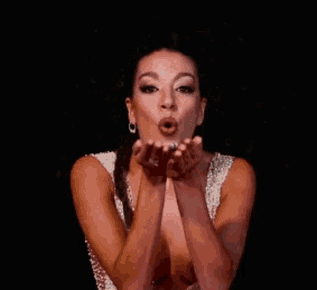 a woman in a silver dress is blowing snow in the air