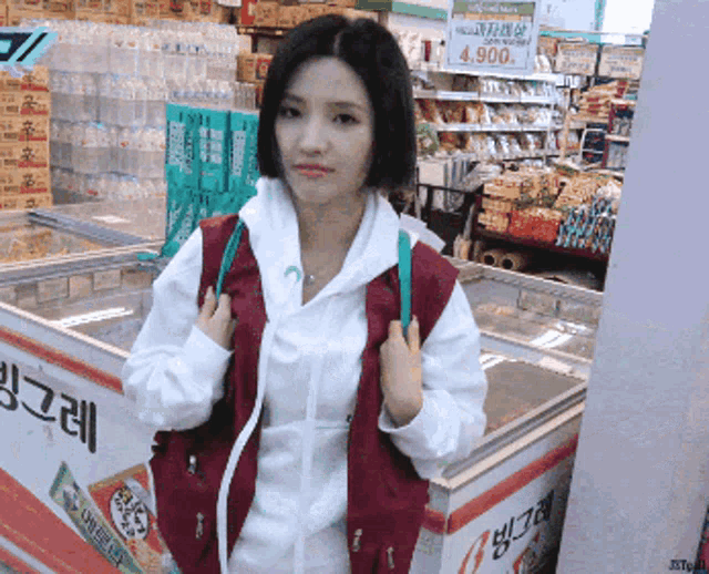 a woman in a red vest is standing in front of a freezer with a sign that says 4900 on it