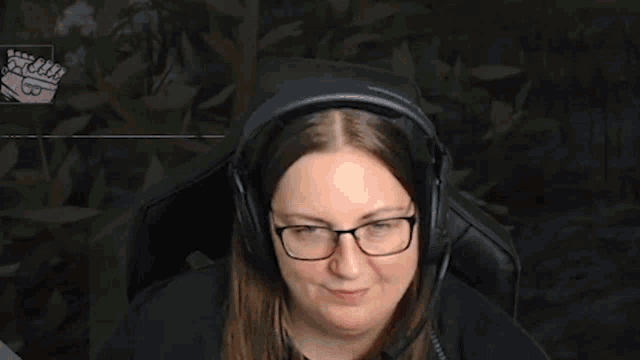 a woman wearing headphones and glasses is making a funny face while sitting in a chair .