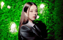 a woman in a suit and tie standing in front of a green wall .