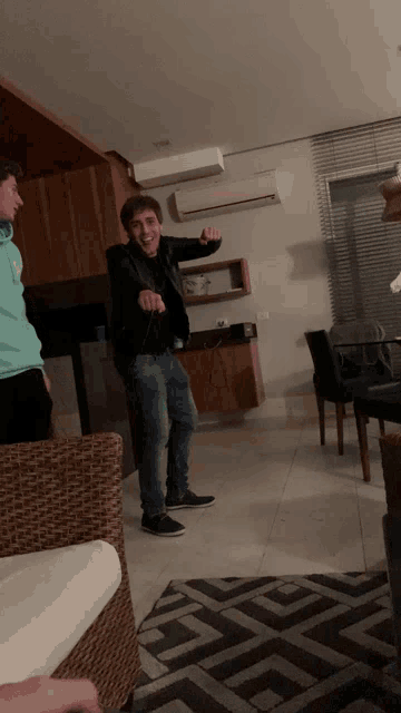 a man in a black jacket stands in a living room