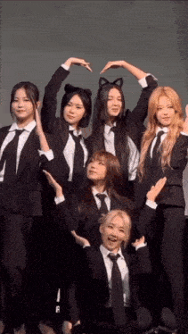 a group of girls in suits and ties are making a heart shape