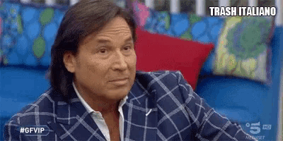 a man in a plaid suit is sitting on a blue couch with a red pillow .