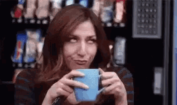a woman is drinking a cup of coffee from a blue mug .