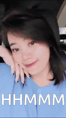 a woman in a blue shirt has her hand on her face and the word hhmmm is on the bottom right