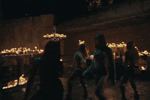 a group of women are dancing in front of a cross with candles on it