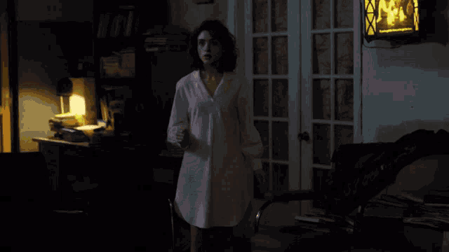a woman in a white shirt is standing in a room