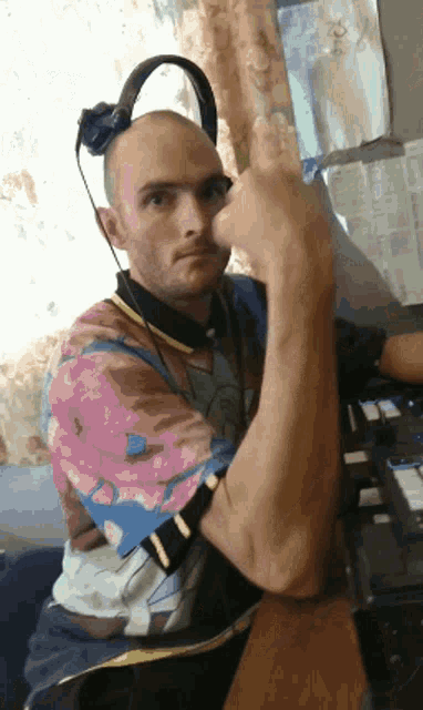 a man wearing headphones and a colorful shirt is giving a thumbs up