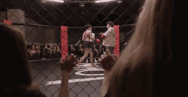 a man and a woman are fighting in a ring with a crowd cheering