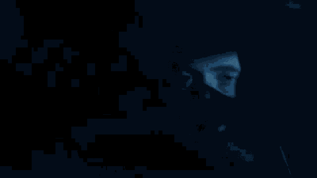 a man in a mask is driving a car in the dark .