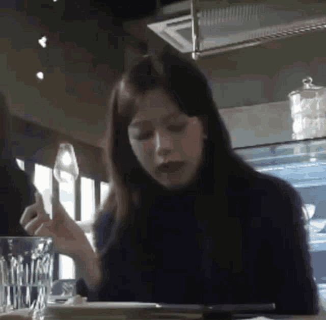 a woman is sitting at a table holding a fork and spoon .