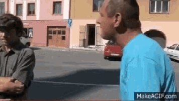 a man in a blue shirt is talking to another man in a parking lot