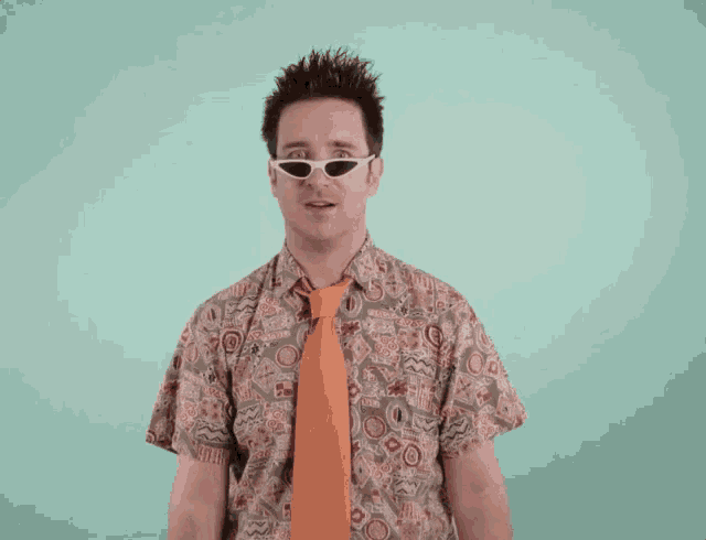 a man wearing sunglasses and an orange tie looks at the camera