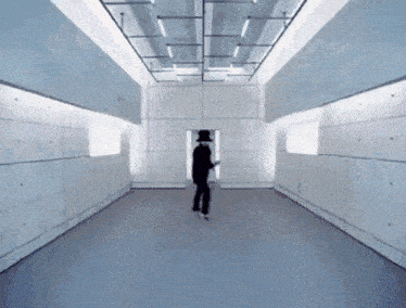 a man in a black top hat is dancing in a large room