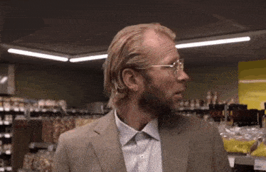 a man wearing glasses and a suit is standing in a store .