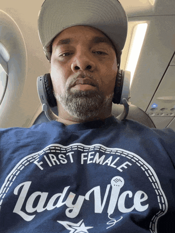 a man wearing headphones and a blue shirt that says first female lady vice