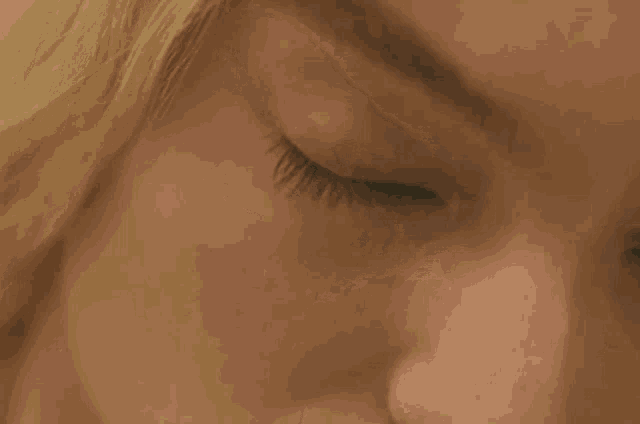 a close up of a woman 's green eyes with a slight smirk on her face .