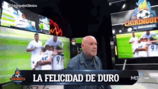 a bald man is sitting in front of a sign that says la felicidad de duro