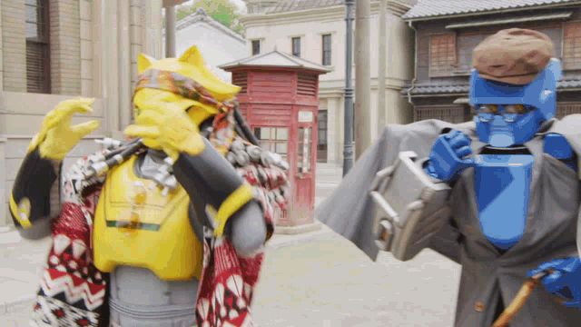 a yellow robot and a blue robot standing next to each other on a street