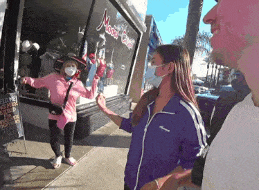 a woman wearing a face mask is standing in front of a model couture store
