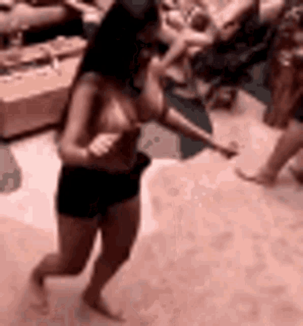 a woman in a bikini is dancing in a room with a group of people .