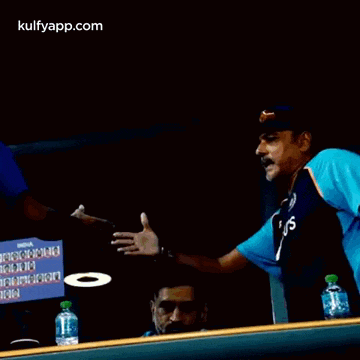 a man in a byju 's jersey is talking to another man in a blue shirt .