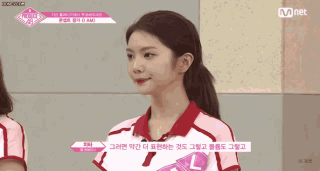 a girl in a red and white shirt is talking to another girl in a pink shirt .