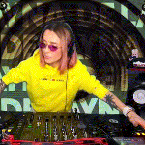 a woman in a yellow tommy hilfiger hoodie is playing music on a dj mixer .